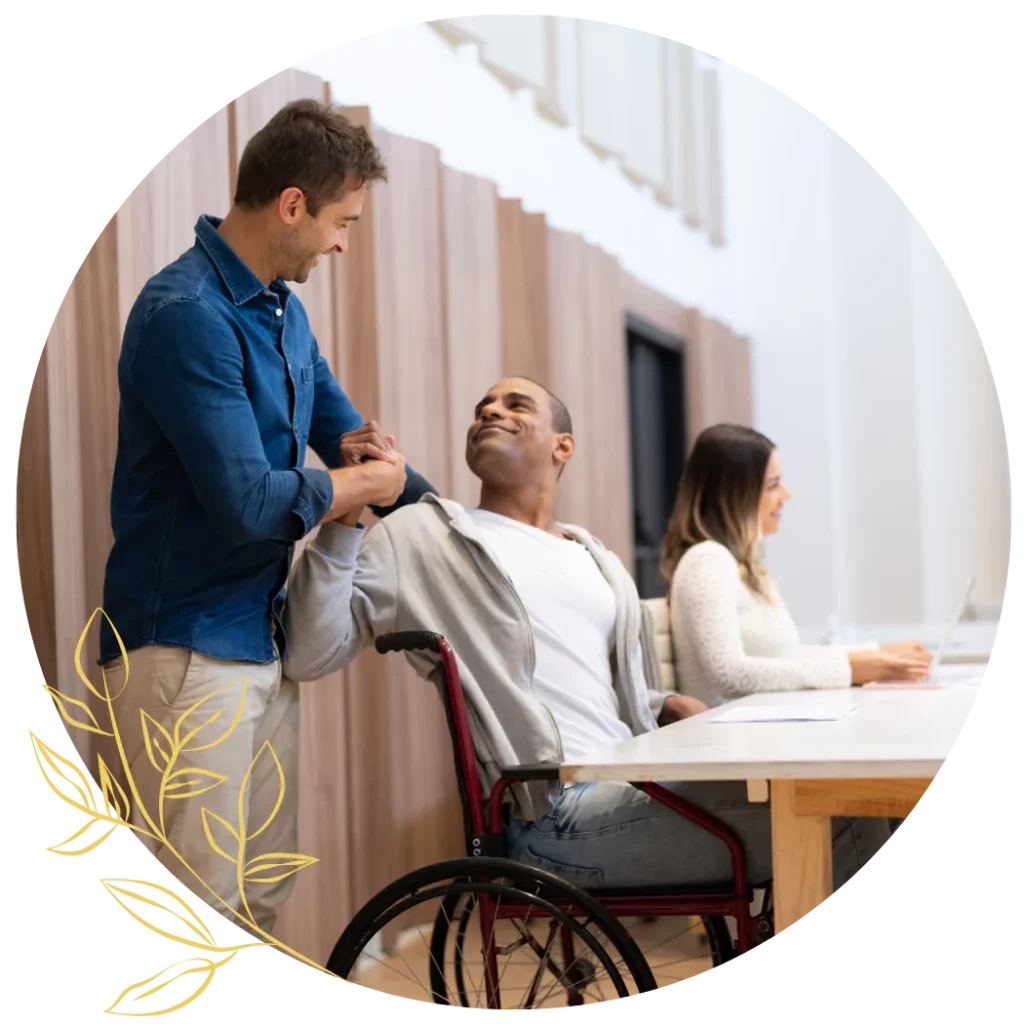A support worker is shaking hands and talking to a disabled man in a wheelchair